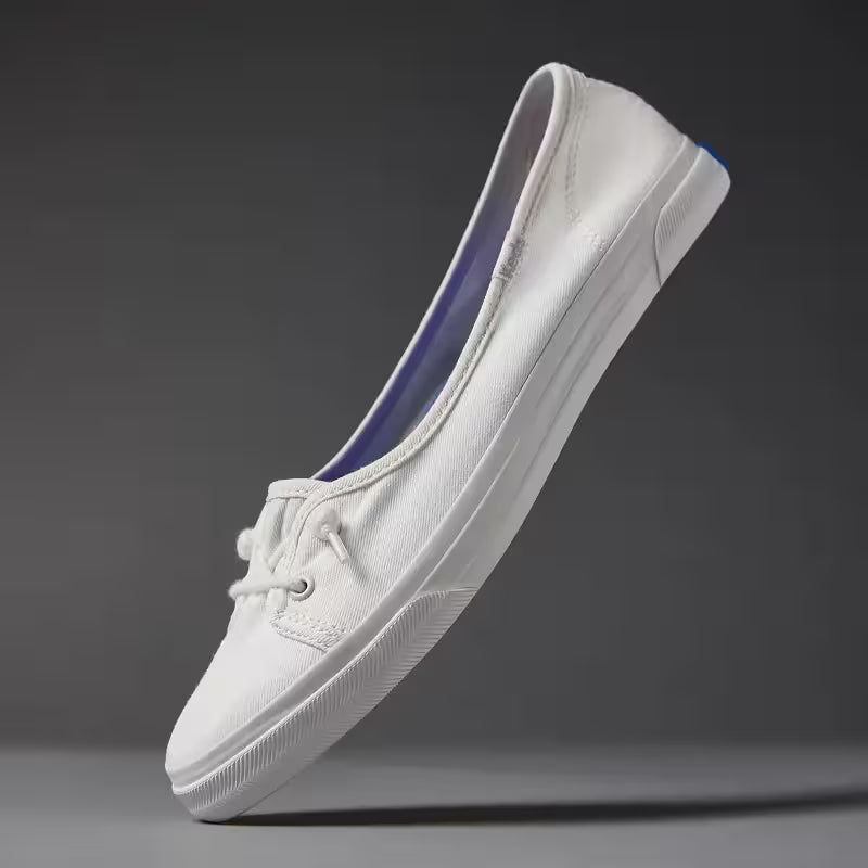 A grey background with a floating Rillax Champ Mini Washed Twill Slip-On in snow white.
